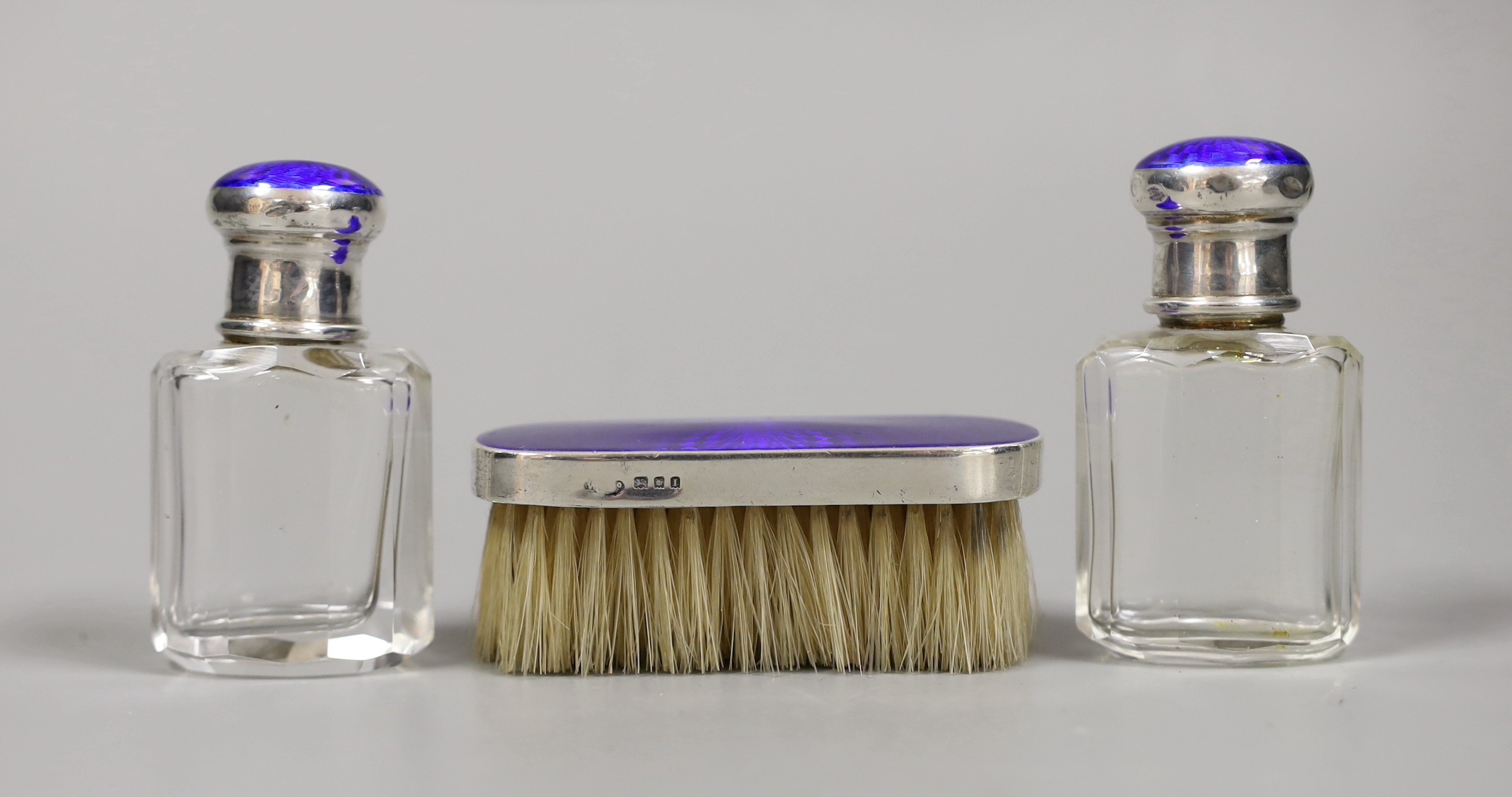 A pair of George V silver and enamel mounted glass scent bottles, 73mm and a small mounted brush, London, 1926.